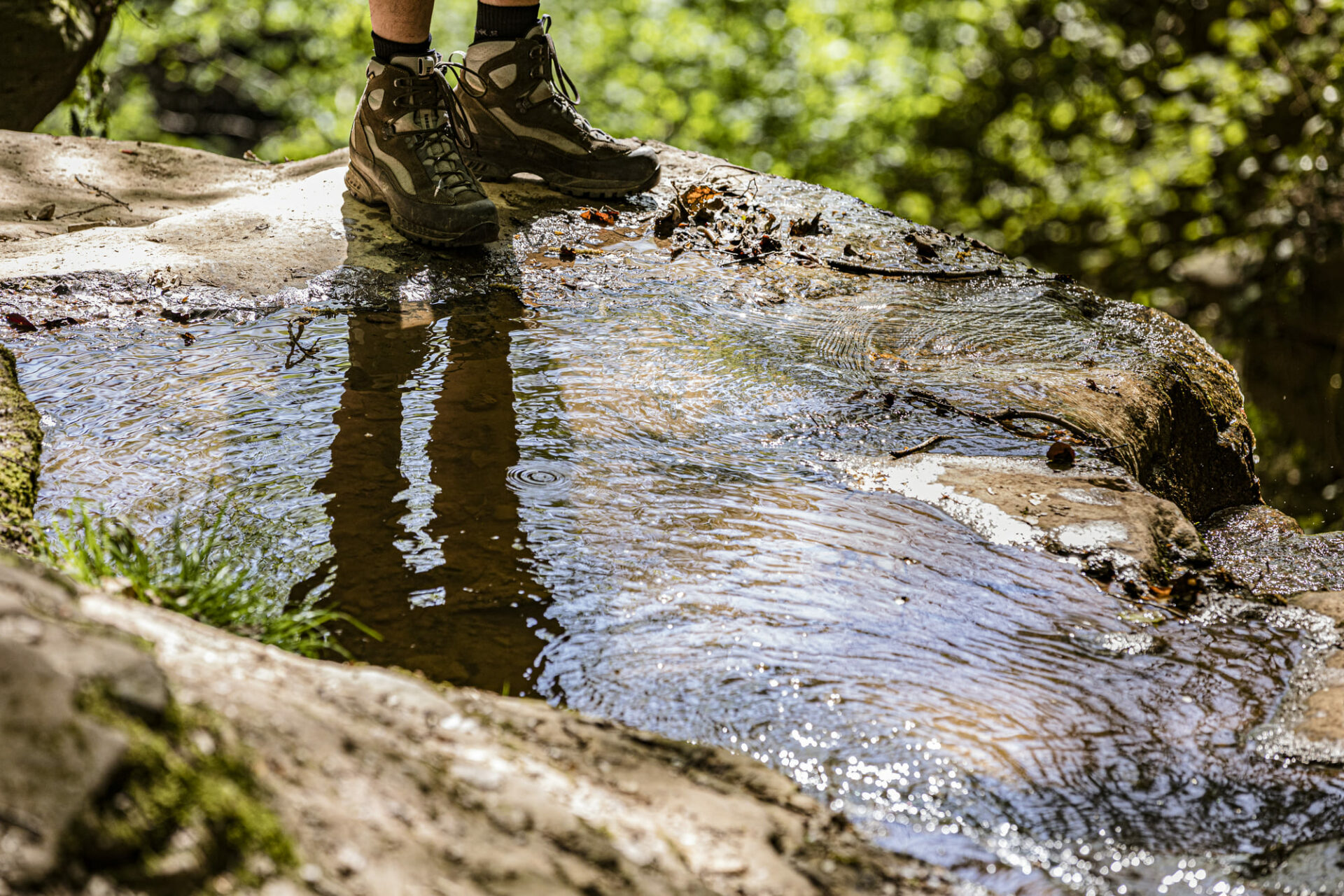 Nahaufnahme von Wanderschuhen an kleinem Bächlein