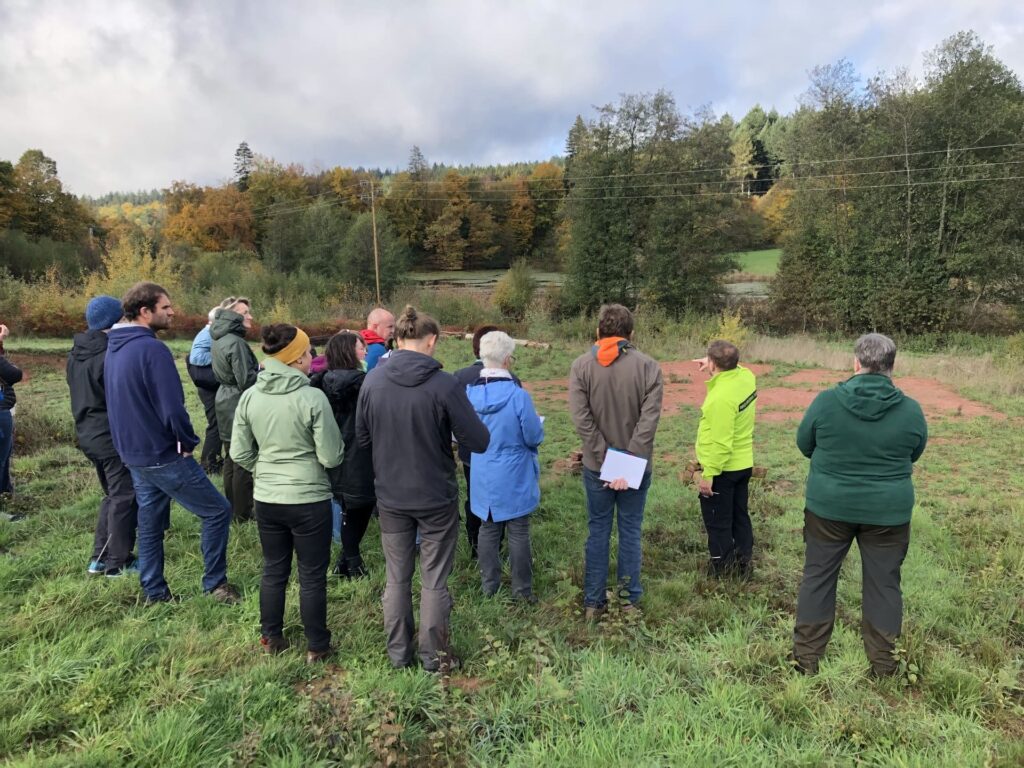 Erwachsene stehen auf einem Feld und nehmen an einer Führung mit einem Naturpark Guide teil