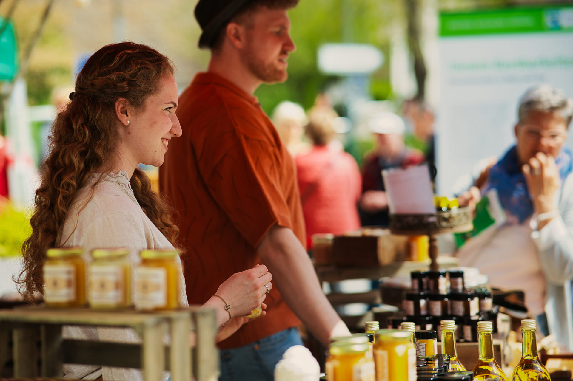 Zwei junge Menschen stehen hinter einem Verkaufsstand auf dem Naturpark-Markt und bieten ihre Honig-Produkte an