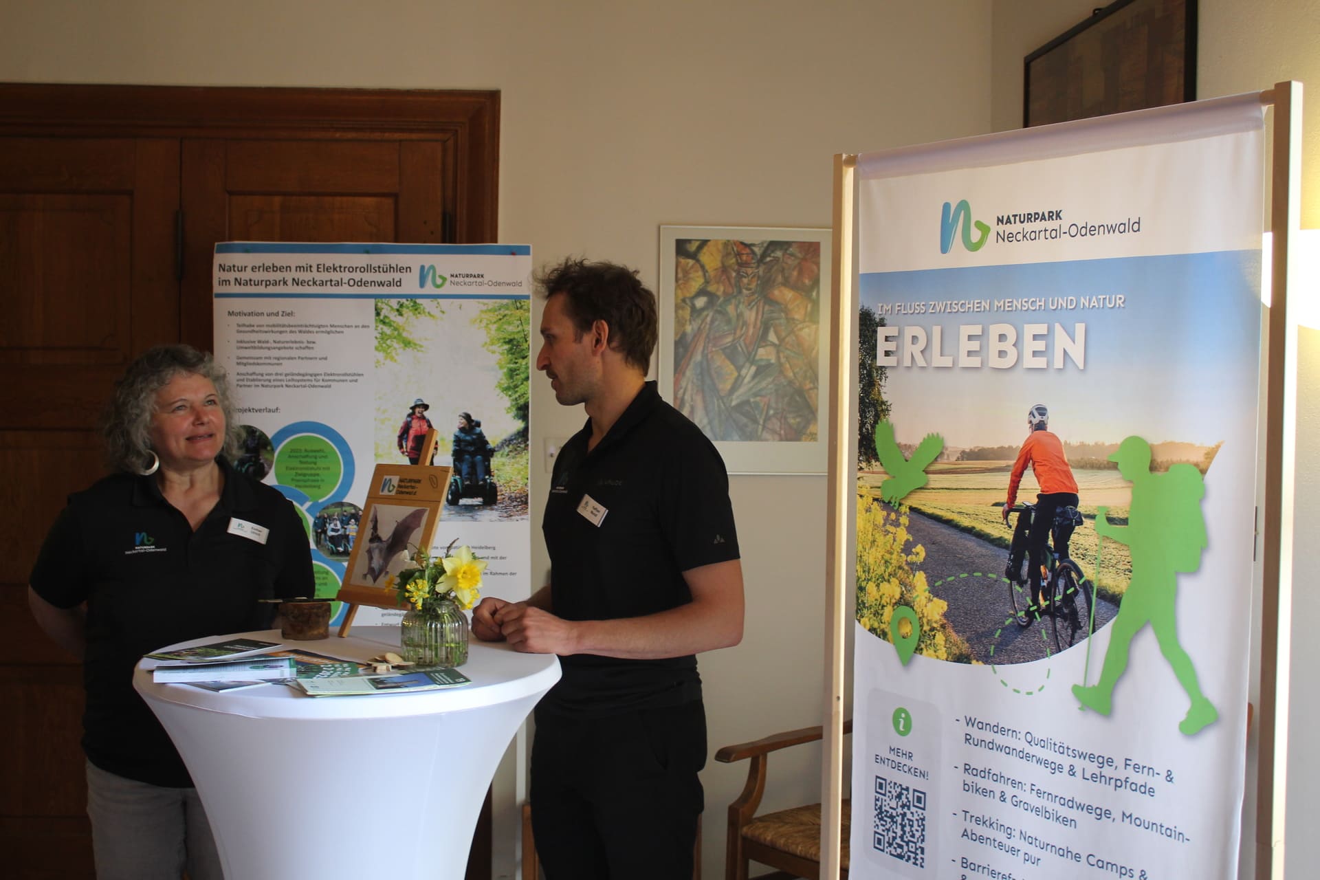 Zwei Teammitglieder mit neuen RollUps im Hintergrund bei der Mitgliederversammlung in Mosbach