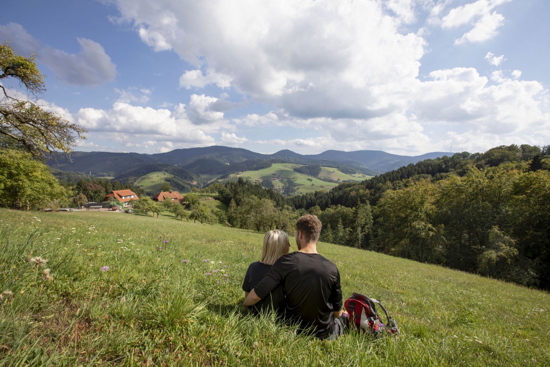 Pärchen sitzt im Gras mit Blick auf Oberharmersbach